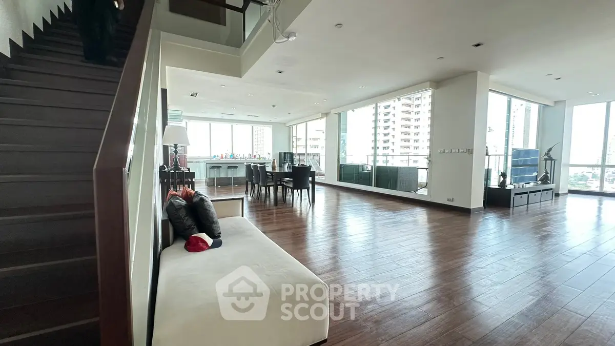 Spacious open-plan living room with wooden flooring and modern decor in a high-rise apartment.
