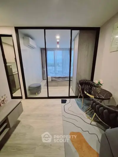 Modern apartment interior with stylish living area and glass partitioned bedroom, featuring elegant furniture and decor.