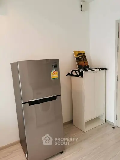 Modern kitchen corner with sleek stainless steel fridge and minimalist cabinet.