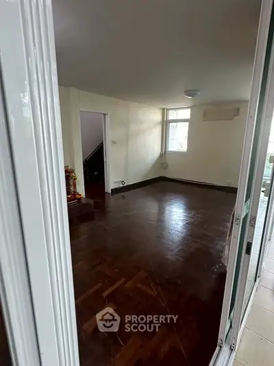 Spacious empty room with wooden flooring and natural light, ideal for customization.