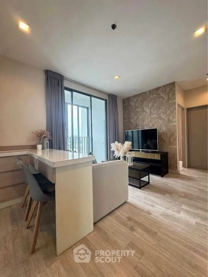 Modern living room with sleek furniture and large window offering natural light and scenic views.