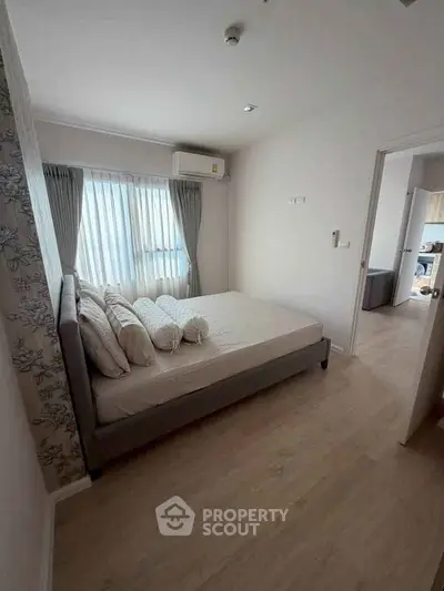 Cozy bedroom with natural light, featuring a comfortable bed and elegant curtains, perfect for relaxation.