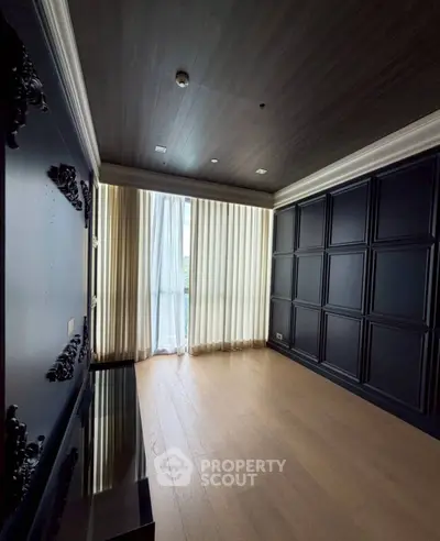 Luxurious empty living room with elegant dark paneling and large window for natural light.