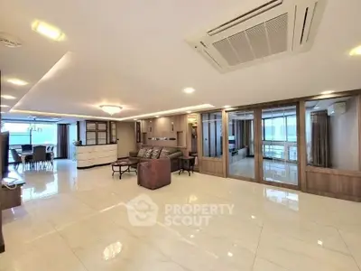 Spacious open-plan living room with modern furnishings and large windows.
