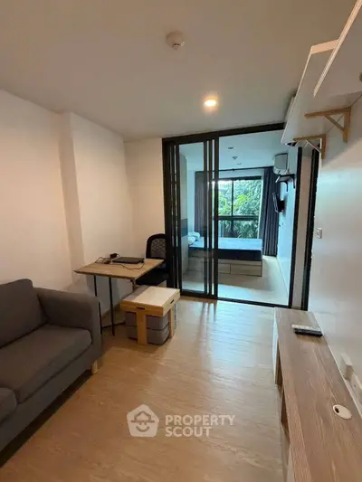 Modern apartment interior with cozy living area and sliding glass doors to bedroom.