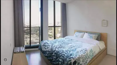 Spacious bedroom with large windows offering stunning city views, modern decor, and natural light.