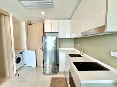 Modern kitchen with sleek appliances and washing machine in compact layout.