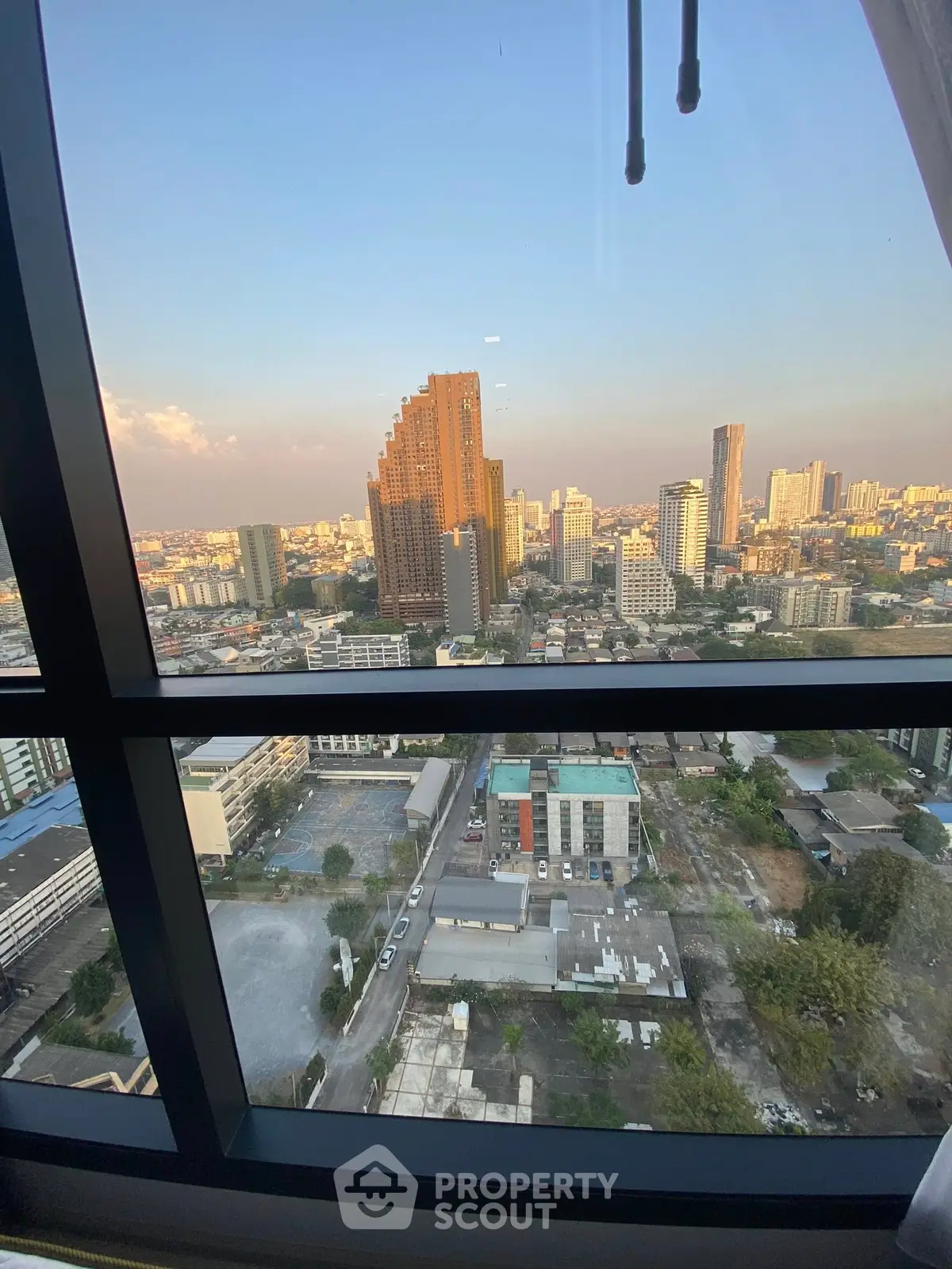 Stunning cityscape view from high-rise window showcasing urban skyline at sunset.