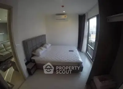 Spacious bedroom with large window and modern furnishings in a stylish apartment.