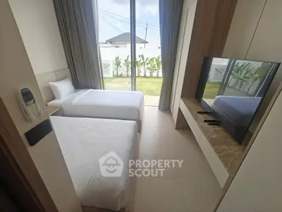 Modern bedroom with twin beds and garden view, featuring sleek design and large windows for natural light.