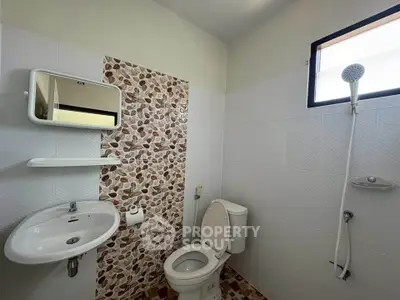 Modern bathroom with stylish tile accent wall and natural light.