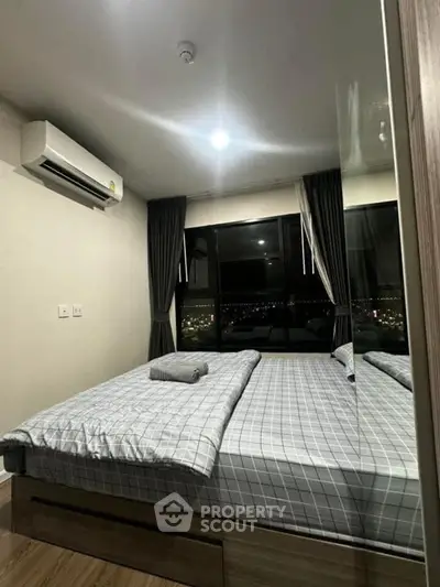 Modern bedroom with city view, featuring a cozy bed and air conditioning.