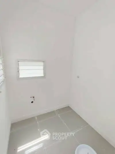 Compact storage room with tiled floor and small window, ideal for organizing essentials.