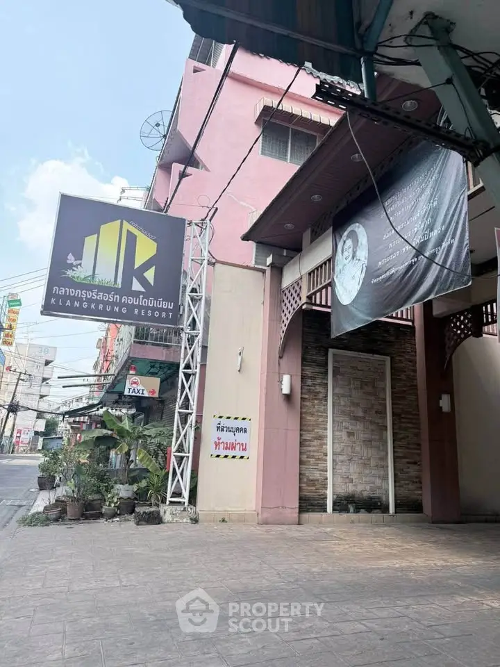 Charming resort entrance with modern signage and urban surroundings.