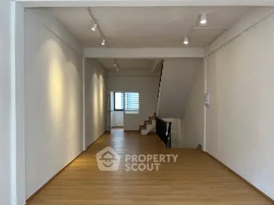 Spacious open-plan interior with wooden flooring and modern lighting, ideal for versatile living space.