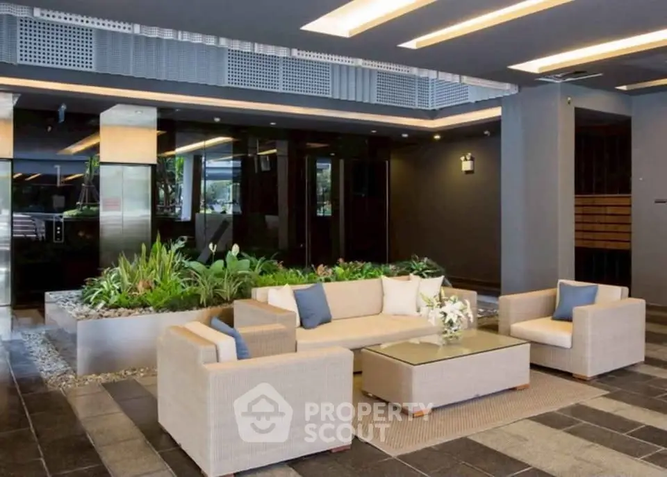 Modern building entrance with stylish seating and lush greenery