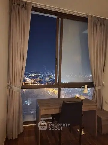 Cozy study area with night city view through large window, perfect for work or relaxation.