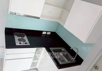 Modern compact kitchen with sleek black countertop and electric stove