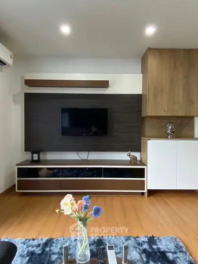 Modern living room with stylish TV unit and wooden flooring, featuring a cozy ambiance and elegant decor.