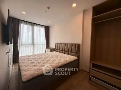 Spacious bedroom with large window and modern furnishings in a stylish apartment.