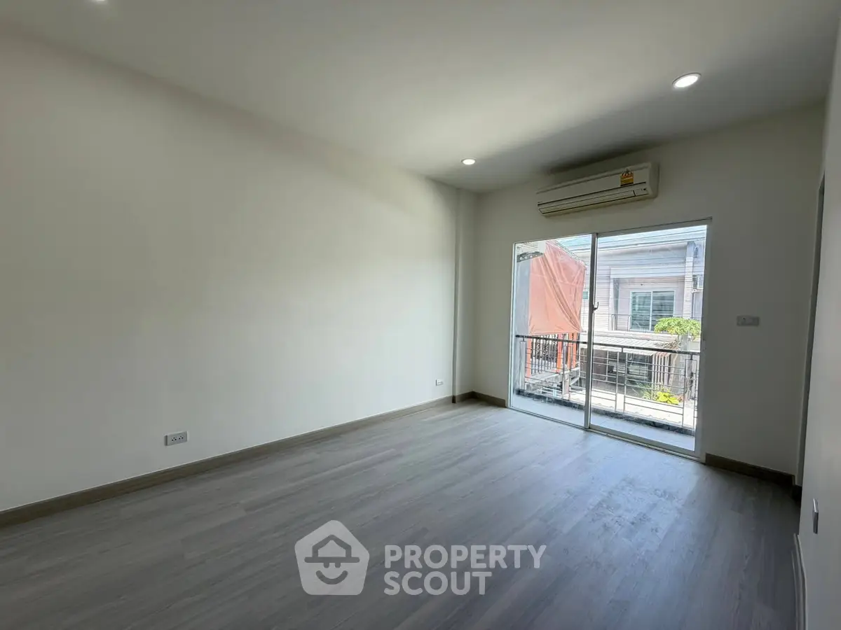Spacious empty room with large window and balcony access, perfect for customization.