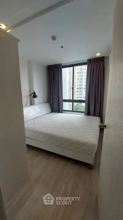 Modern bedroom with large window and minimalist decor in urban apartment