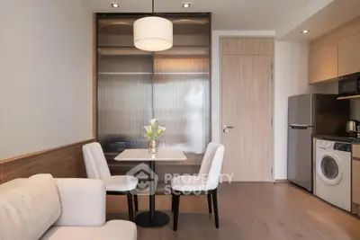 Modern apartment interior with cozy dining area and compact kitchen featuring washing machine and fridge.