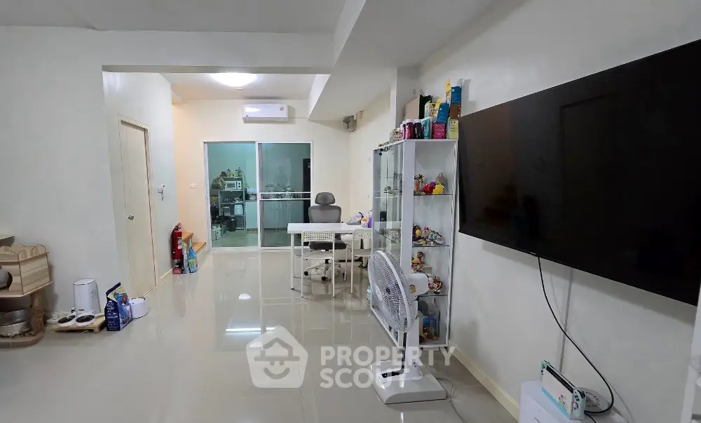 Spacious living room with modern decor and large TV, ideal for family gatherings.