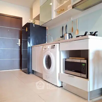Modern kitchen with sleek appliances and washing machine in compact layout.
