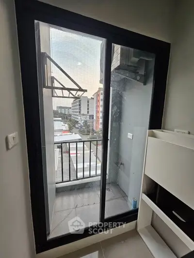 Modern apartment balcony with sliding glass door and urban view, perfect for city living.