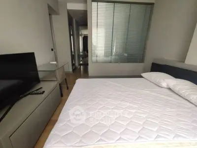 Modern bedroom with sleek design and glass partition, featuring a TV and minimalist decor.