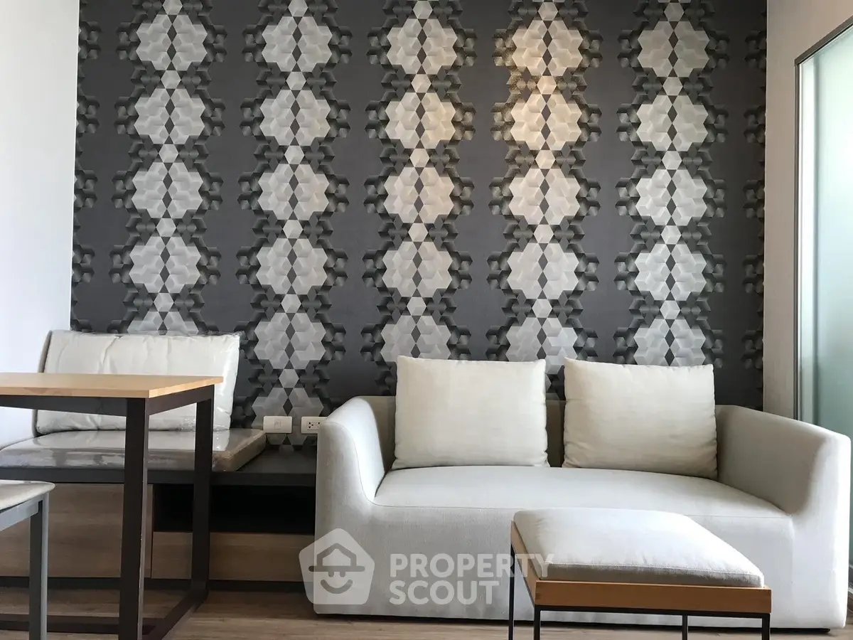 Modern living room with stylish geometric wallpaper and cozy white sofa.