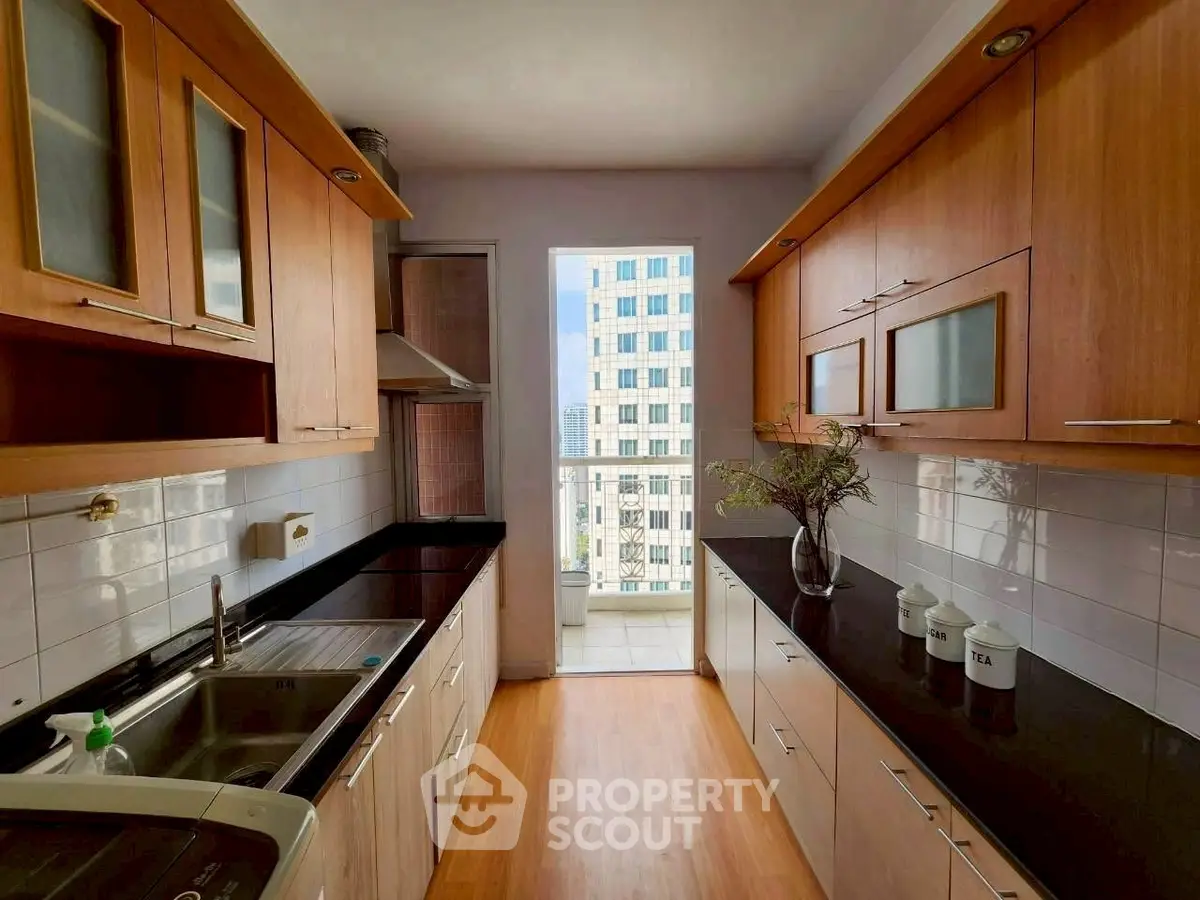 Modern kitchen with sleek black countertops and wooden cabinets, offering a bright and airy atmosphere.