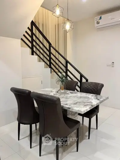 Modern dining area with marble table and elegant chairs under stylish lighting.