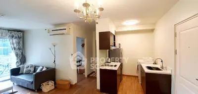 Modern open-layout living room with kitchen, featuring elegant chandelier and cozy seating area.