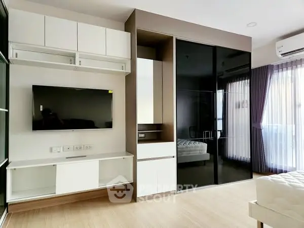 Modern living room with sleek TV unit and large windows for natural light.