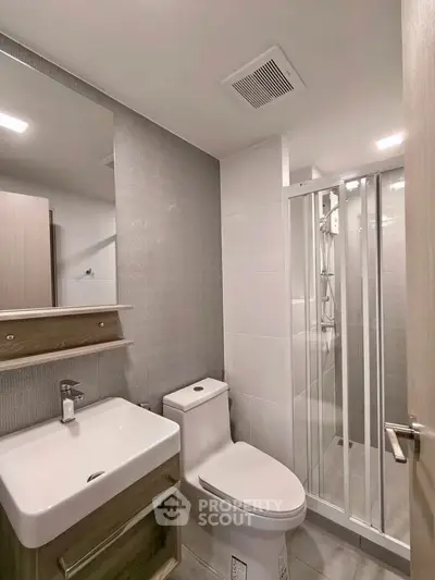Modern bathroom with sleek fixtures and glass shower enclosure in a contemporary apartment.