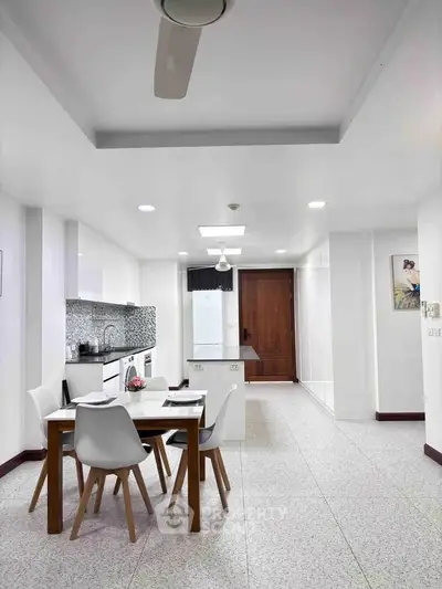 Modern kitchen with dining area featuring sleek white cabinets and stylish dining set.