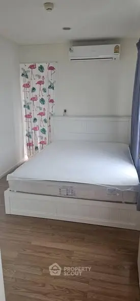 Cozy bedroom with air conditioning and wooden flooring, featuring a stylish flamingo curtain.