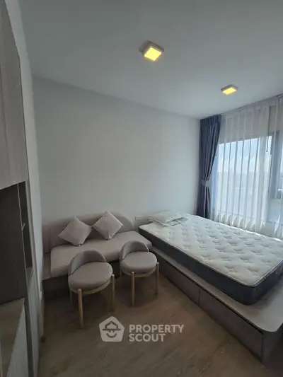 Modern bedroom with minimalist decor, featuring a cozy bed and stylish seating area, perfect for urban living.