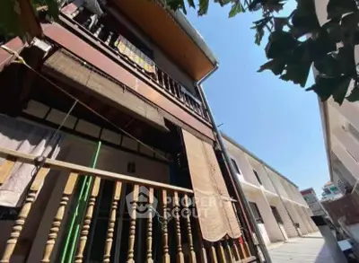 Charming multi-story building with wooden accents and outdoor balcony in a sunny neighborhood.