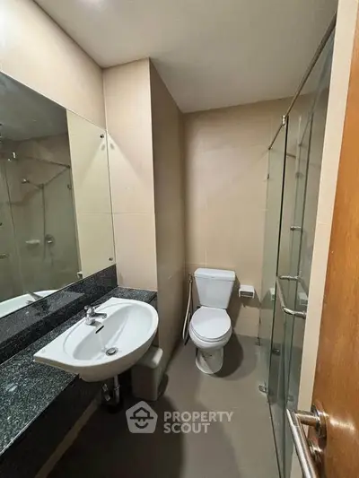 Modern bathroom with glass shower and sleek fixtures in a contemporary apartment.