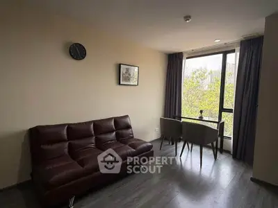 Modern living room with sleek sofa and dining area, featuring large window with garden view.