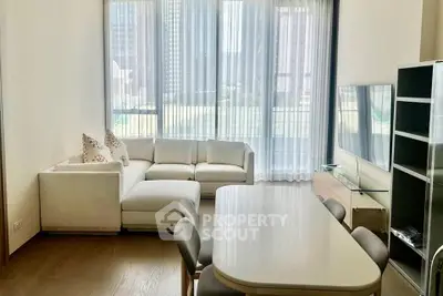 Spacious modern living room with large windows and elegant furniture in a high-rise apartment.