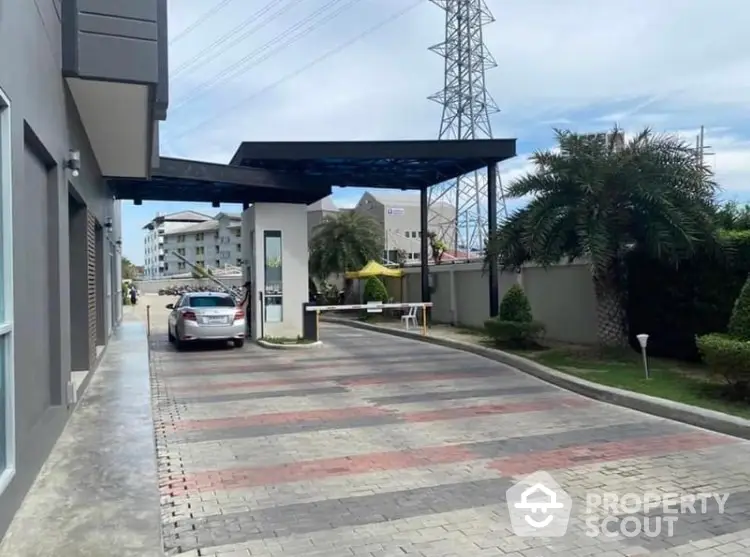 Modern gated entrance with driveway and landscaped surroundings in a residential area.