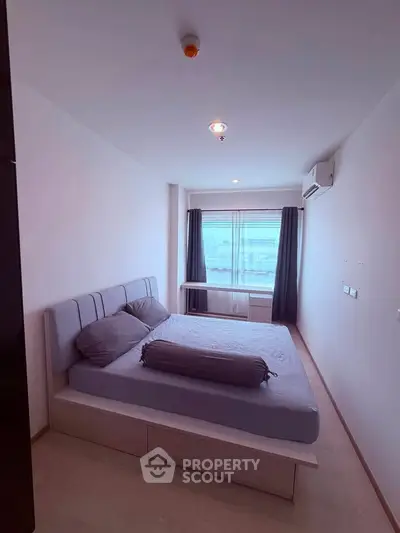 Modern bedroom with large window and minimalist decor in a cozy apartment.