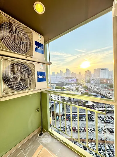 Stunning balcony view with city skyline and sunset, featuring air conditioning units.