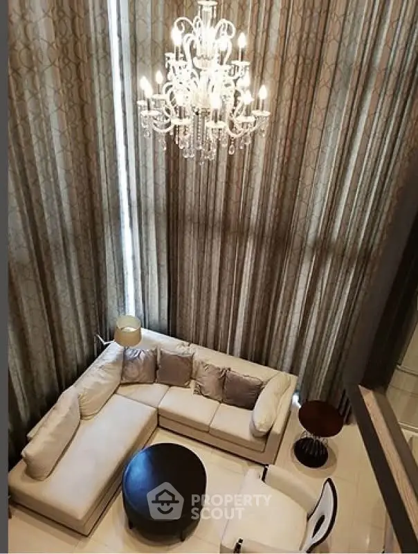 Luxurious high-ceiling living room with elegant chandelier and plush sectional sofa.