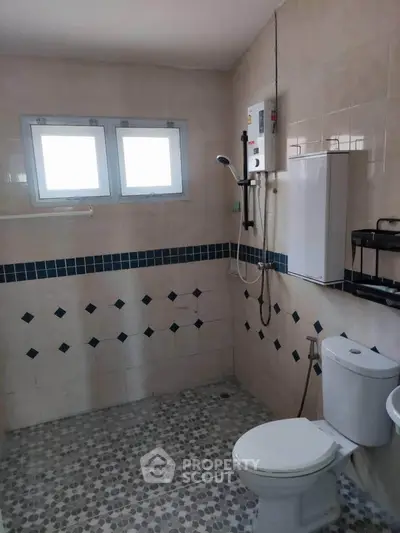 Spacious bathroom with modern fixtures and tiled walls, featuring a water heater and dual windows for natural light.