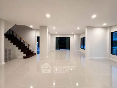 Spacious modern living room with sleek tile flooring and elegant staircase, perfect for contemporary living.